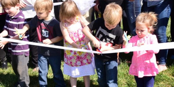 Children cutting a ribbon at the Eastern Scholar House ribbon cutting.