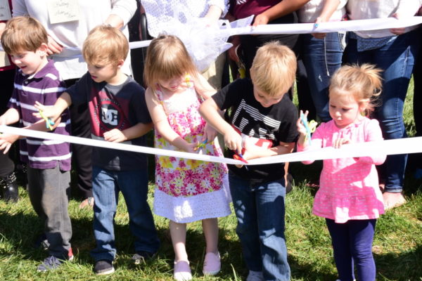 Children cutting a ribbon at the Eastern Scholar House ribbon cutting.