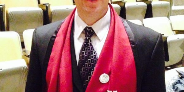 CEO Jim King is standing in an auditorium wearing a Harvard University scarf.