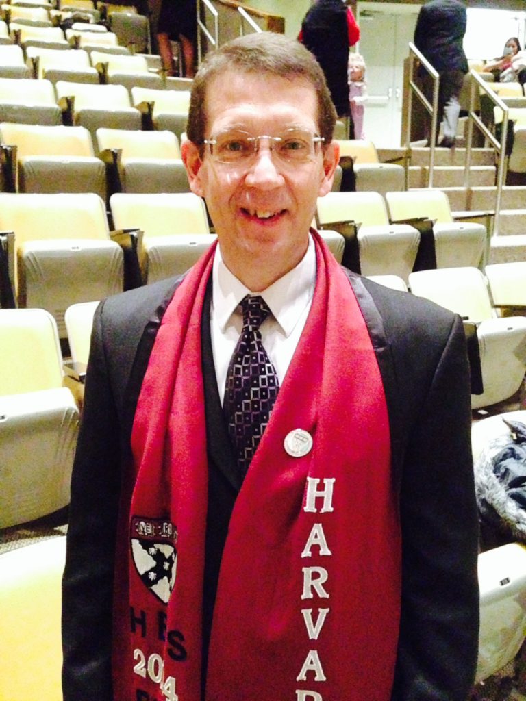 CEO Jim King is standing in an auditorium wearing a Harvard University scarf.