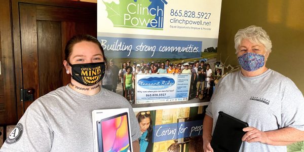 Two caucasian women with Covid-19 masks on are standing in front of a Clinch Powell pull up banner.