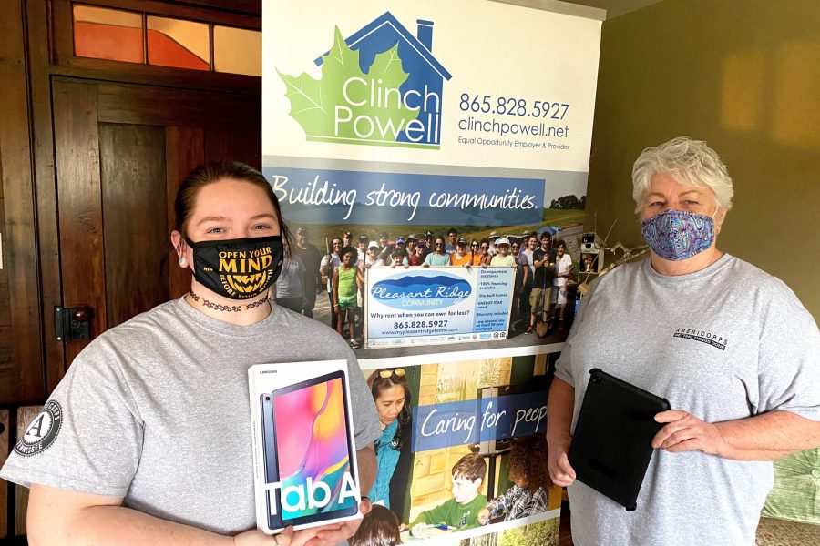 Two caucasian women with Covid-19 masks on are standing in front of a Clinch Powell pull up banner.