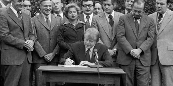 A group of people are standing around someone signing the Community Reinvestment Act at a table.