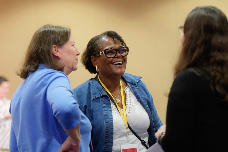 An African American woman is smiling and listening to a caucasian woman speak at a Fahe annual event.