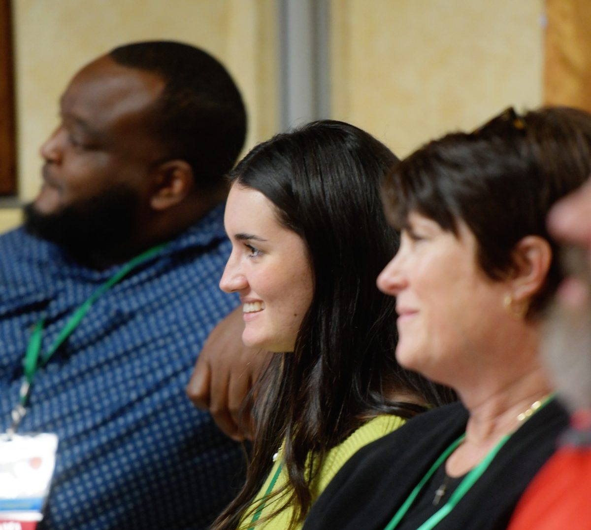 A group of four people are sitting smiling listening to someone speak at an annual event.